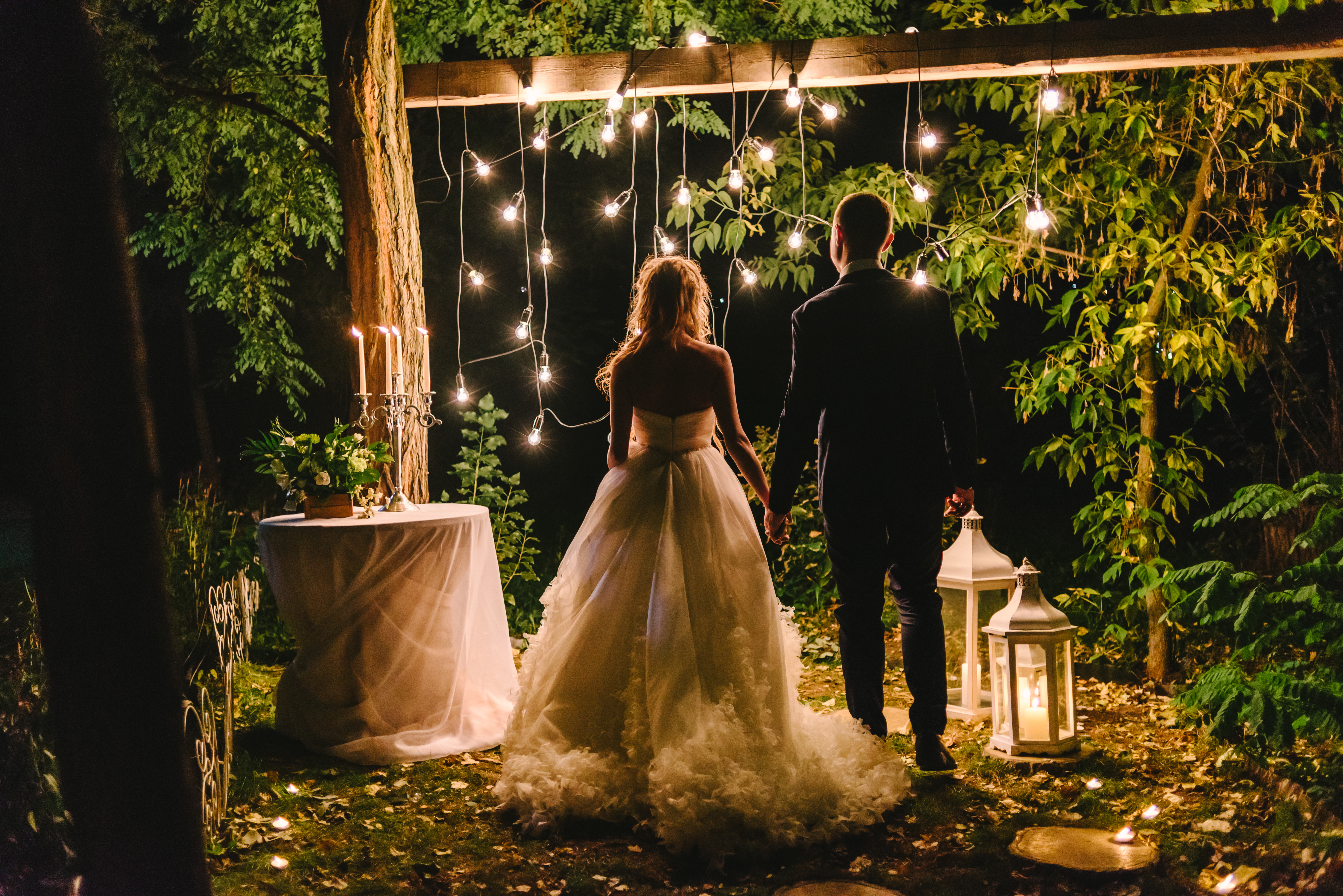 Night wedding ceremony with candles, lanterns and lamps on tree.